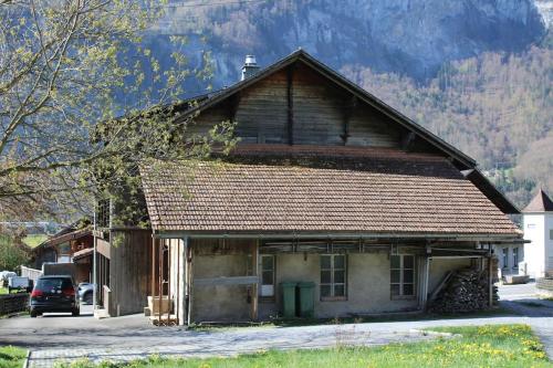 an old wooden house with a mountain in the background at Family-friendly chalet apt with balcony in Meiringen