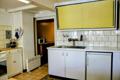a kitchen with white cabinets and a sink at Family-friendly chalet apt with balcony in Meiringen