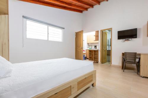 a bedroom with a large white bed and a kitchen at Lindo loft en corazón de Medellín Pet Friendly 206 in Medellín