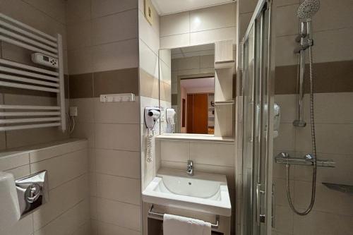 a bathroom with a sink and a shower and a mirror at Domaine de Pyrène in Cauterets