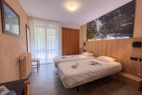 a hotel room with two beds and a large window at Domaine de Pyrène in Cauterets