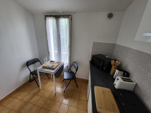 a small kitchen with a table and chairs in a room at Superbe studio centre-ville in Drancy