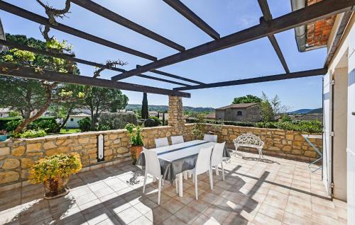 a patio with a table and chairs and a stone wall at Lovely Home In Saint-Julien-Les-Rosie in Saint Julien Les Rosiers