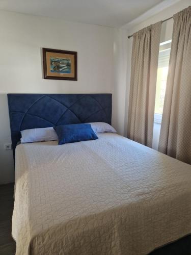 a bedroom with a bed with a blue headboard and a window at Apartment Una s dvije terase in Privlaka