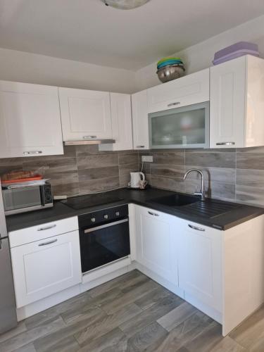 a kitchen with white cabinets and a sink at Apartment Una s dvije terase in Privlaka