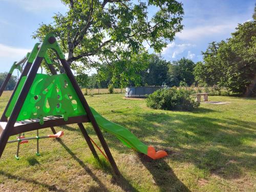un toboggan vert dans une cour avec un arbre dans l'établissement La Caillade, à Bayac