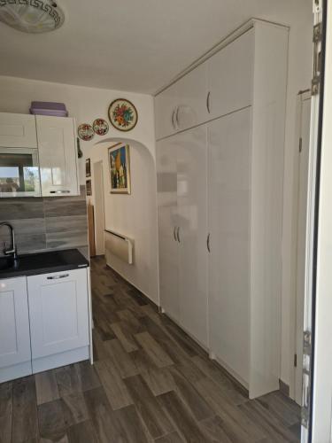 a kitchen with white cabinets and a wooden floor at Apartment Una s dvije terase in Privlaka