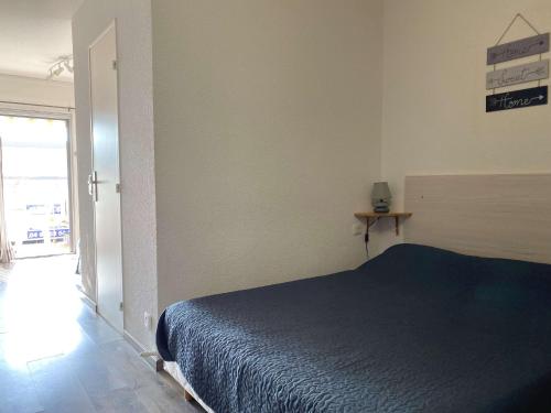 Un dormitorio con una cama azul y una ventana en Appartement Balaruc-les-Bains, 1 pièce, 2 personnes - FR-1-553-35, en Balaruc-les-Bains