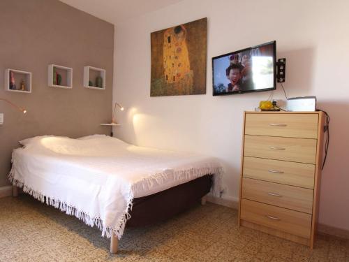 ein Schlafzimmer mit einem Bett und einer Kommode mit einem TV in der Unterkunft Studio Balaruc-les-Bains, 1 pièce, 2 personnes - FR-1-553-41 in Balaruc-les-Bains