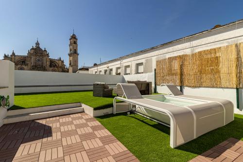 um pátio exterior com um banco branco e relva em Allo Apartments Arroyo Catedral em Jerez de la Frontera