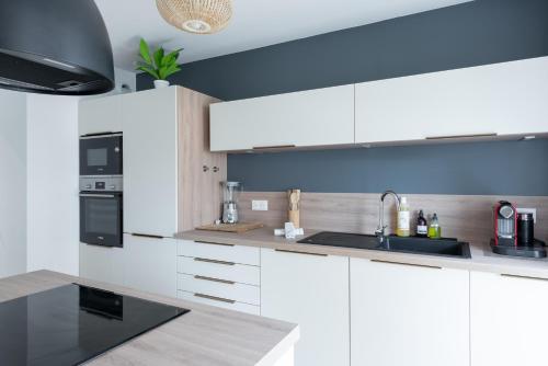 une cuisine avec des armoires blanches et un évier dans l'établissement Le cinquième ciel - 75m2 avec garage privé, à Villeurbanne