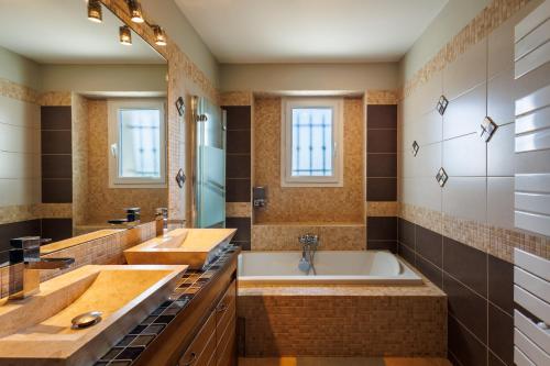 een badkamer met 2 wastafels en een groot bad bij La Villa Mont Ventoux - piscine jacuzzi in Carpentras