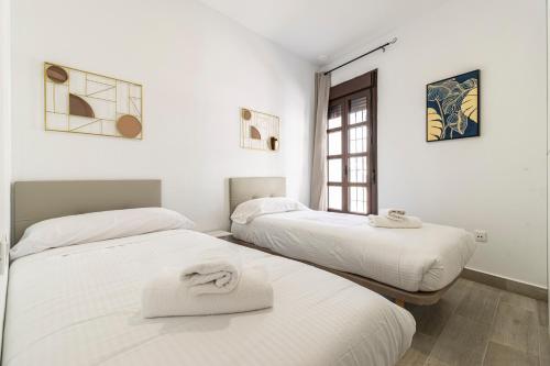 two beds in a room with two towels on them at Allo Apartments Arroyo Catedral in Jerez de la Frontera