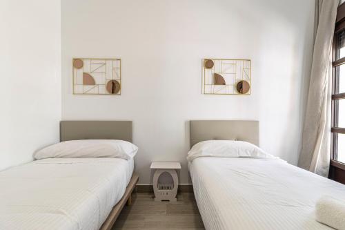 two beds in a room with white walls at Allo Apartments Arroyo Catedral in Jerez de la Frontera
