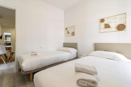 two beds in a room with white walls at Allo Apartments Arroyo Catedral in Jerez de la Frontera