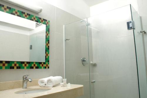 y baño con ducha, lavabo y espejo. en Hotel Genova Centro en Barranquilla
