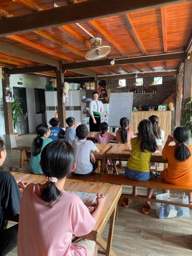 a group of people sitting on benches listening to a chef at Homestay Chinh Bi in Yên Bái