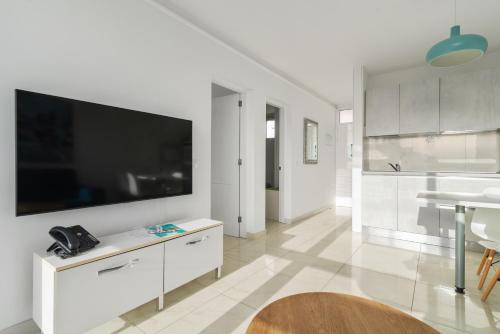 a white kitchen with a large tv on the wall at Mariposa Del Sol in Patalavaca