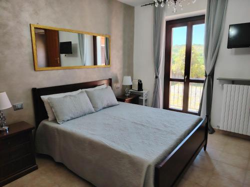 Schlafzimmer mit einem Bett mit einem Spiegel und einem Fenster in der Unterkunft VILLA SAMUELA in Neive