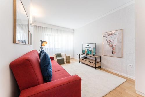 a living room with a red couch and a chair at GuestReady - Geometric Dawn in Vila do Conde in Vila do Conde