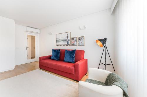 a living room with a red chair and blue pillows at GuestReady - Geometric Dawn in Vila do Conde in Vila do Conde