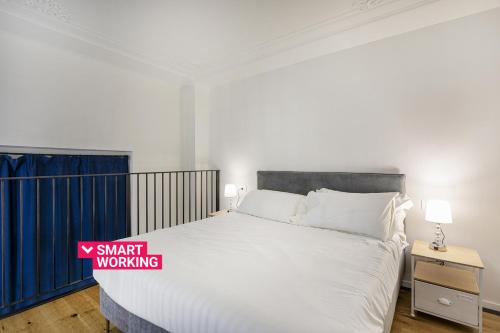 ein Schlafzimmer mit einem großen weißen Bett und einem Nachttisch in der Unterkunft Zecca Contemporary Loft by Wonderful Italy in Genua