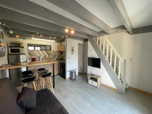 Il comprend un salon avec un canapé, une cuisine et des escaliers. dans l'établissement Maison à Capbreton: 20m plage, terrasse, parking, animaux ok - FR-1-413-159, à Capbreton