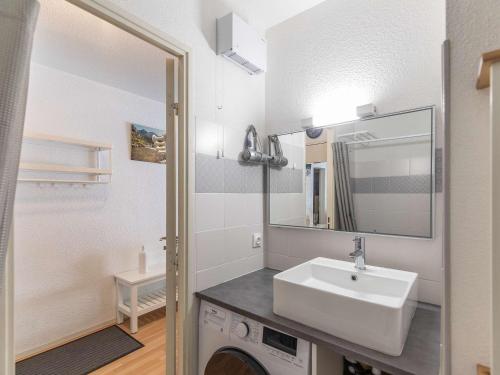 Un baño blanco con lavabo y espejo. en Appartement T2 à Cauterets, proche télécabine avec parking et local ski - FR-1-401-198, en Cauterets