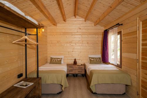 two beds in a room with wooden walls at Bir Dem Urla in Urla