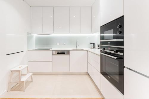 uma cozinha branca com um lavatório e um fogão em GuestReady - Amazing Modern home near the beach em Vila Nova de Gaia