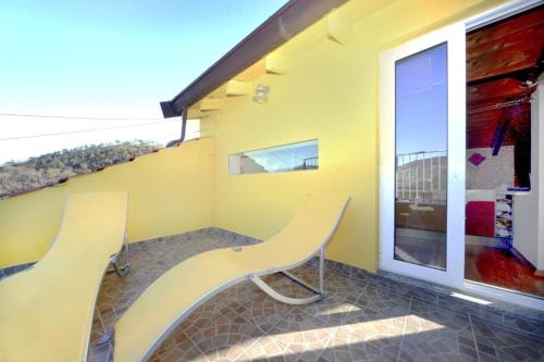 two yellow chairs on a balcony with a window at La vita è bella - Noli in Noli