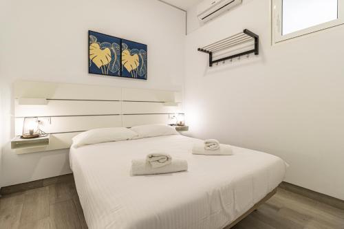 a white bedroom with a bed with two towels on it at Allo Apartments Arroyo Catedral in Jerez de la Frontera