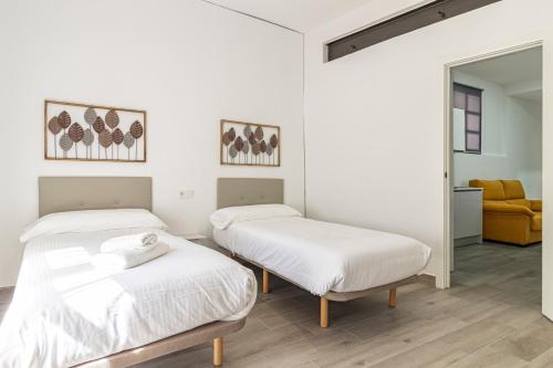 two beds in a room with white walls at Allo Apartments Arroyo Catedral in Jerez de la Frontera