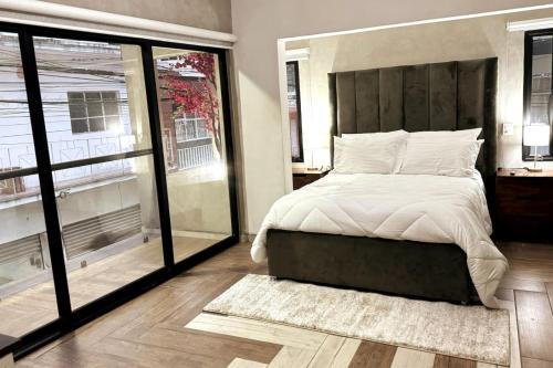 ein Schlafzimmer mit einem großen Bett und großen Fenstern in der Unterkunft Tranquil refuge in Xalapa, 3BR 1BA apt for 6 in Xalapa