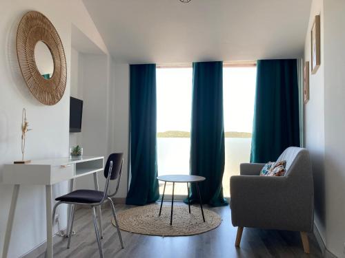 sala de estar con cortinas azules, silla y escritorio en La Bruyère en Rochefort-du-Gard