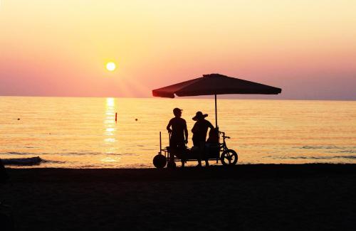 two people sitting under an umbrella on the beach at Blumont Aparthotel Durres in Durrës