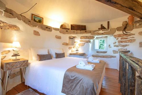 een slaapkamer met een wit bed in een kamer met stenen muren bij Quinta Molinum Ad Mare in Boliqueime