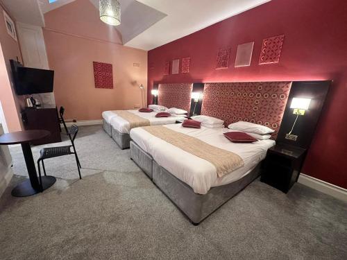 two beds in a hotel room with red walls at Acacia Hotel in London