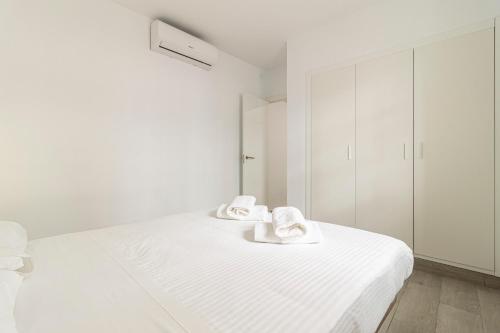a white bedroom with two towels on a bed at Allo Apartments Arroyo Catedral in Jerez de la Frontera