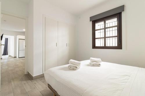 a white bedroom with a large bed and a window at Allo Apartments Arroyo Catedral in Jerez de la Frontera