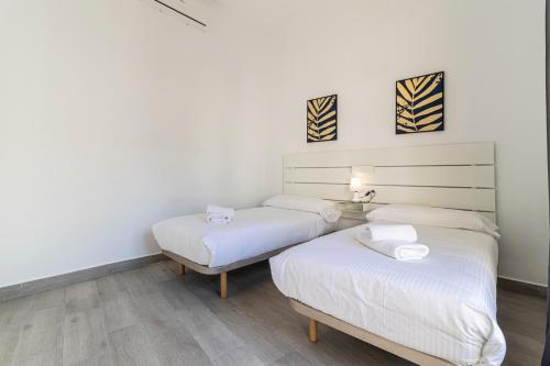 two beds in a room with white walls and wood floors at Allo Apartments Arroyo Catedral in Jerez de la Frontera