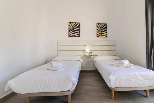 two beds in a room with white walls at Allo Apartments Arroyo Catedral in Jerez de la Frontera