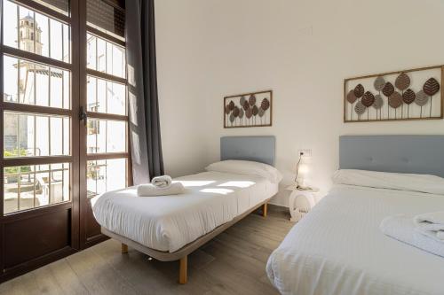a bedroom with two beds and a window at Allo Apartments Arroyo Catedral in Jerez de la Frontera