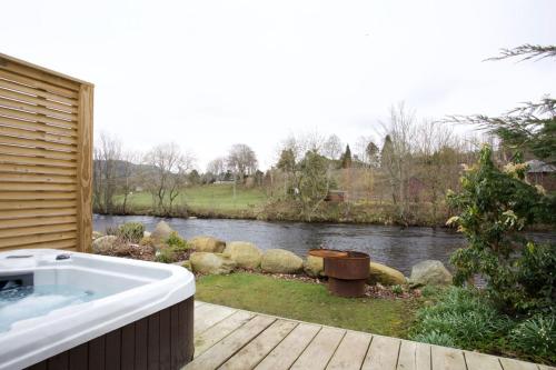 een ligbad op een terras naast een rivier bij Braidhaugh Holiday Lodge and Glamping Park in Crieff