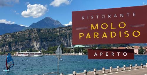a sign for molo marbella and a body of water at Hotel Paradiso Conca d'Oro in Nago-Torbole