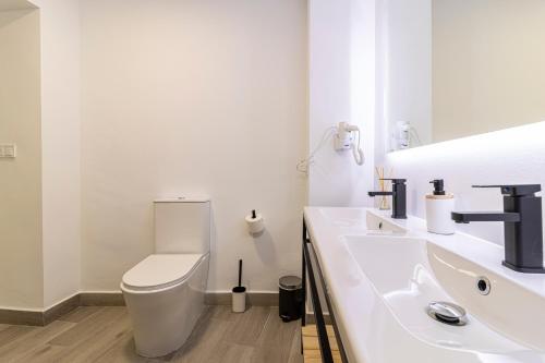 a white bathroom with a toilet and a sink at Allo Apartments Arroyo Catedral in Jerez de la Frontera
