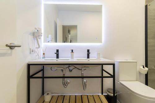 a bathroom with a sink and a mirror and a toilet at Allo Apartments Arroyo Catedral in Jerez de la Frontera