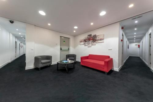 a waiting room with a red couch and two chairs at Hotel Gabriel y Galán in Salamanca