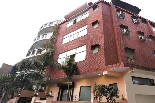 a red brick building with a tall building at Collection O Ramji 7 Grand Near Tdi Mall in New Delhi