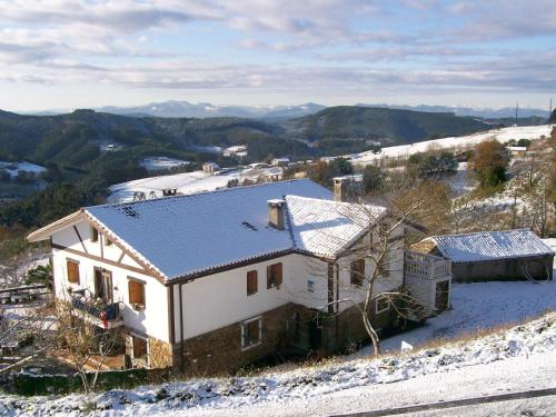ein Haus auf einem Hügel mit Schnee auf dem Boden in der Unterkunft Agroturismo Kasa Barri in Bermeo